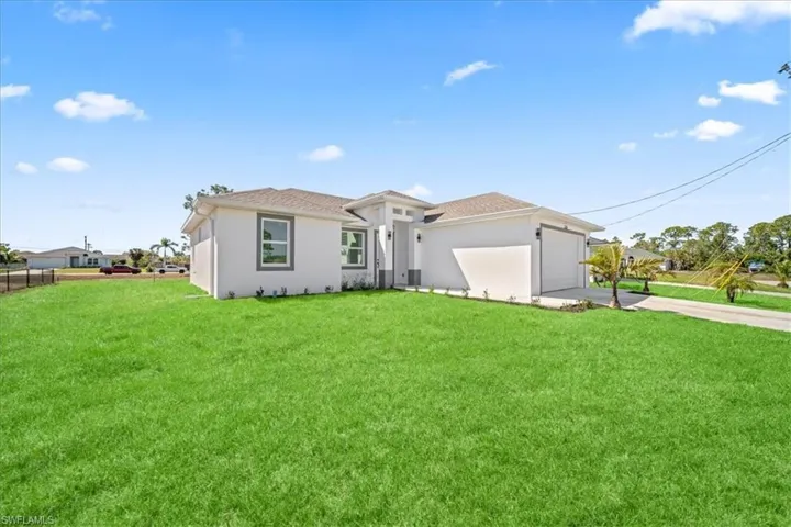View of front of house with driveway, a garage, stucco siding, and a front yard