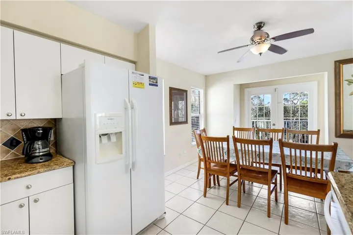 Kitchen featuring tasteful backsplash, dark stone countertops, white fridge with ice dispenser, and white cabinets