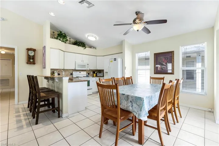 Tiled dining area with ceiling fan and vaulted ceiling
