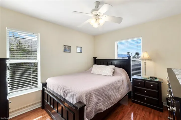 Bedroom featuring dark hardwood / wood-style floors, multiple windows, and ceiling fan