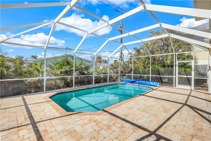 View of pool featuring glass enclosure and a patio area