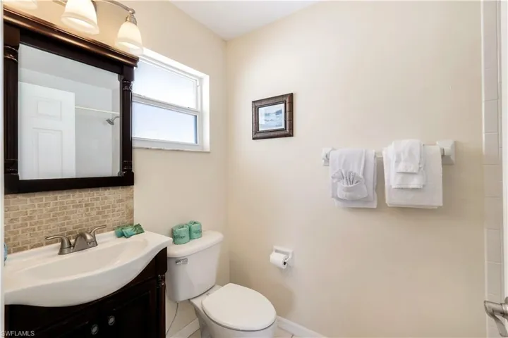 Bathroom with a shower, decorative backsplash, vanity, and toilet