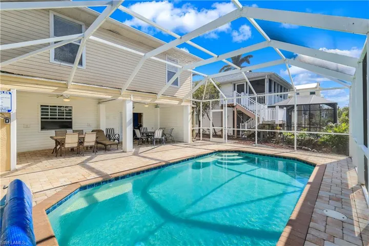 View of swimming pool with glass enclosure, ceiling fan, and a patio area
