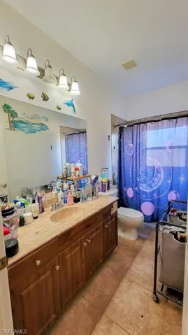 Full bathroom with vanity, a shower with shower curtain, and light tile patterned floors