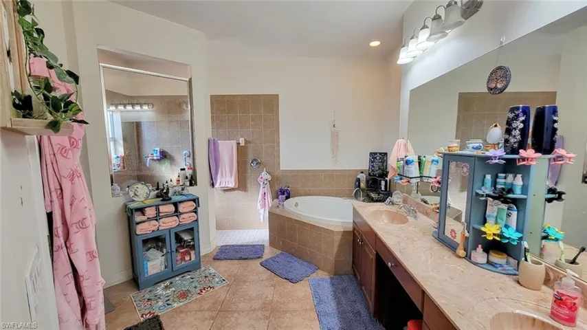 Bathroom featuring double vanity, a walk in shower, a garden tub, and light tile patterned floors