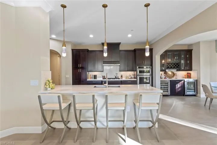 Kitchen with arched walkways, a breakfast bar area, glass insert cabinets, tasteful backsplash, and a peninsula