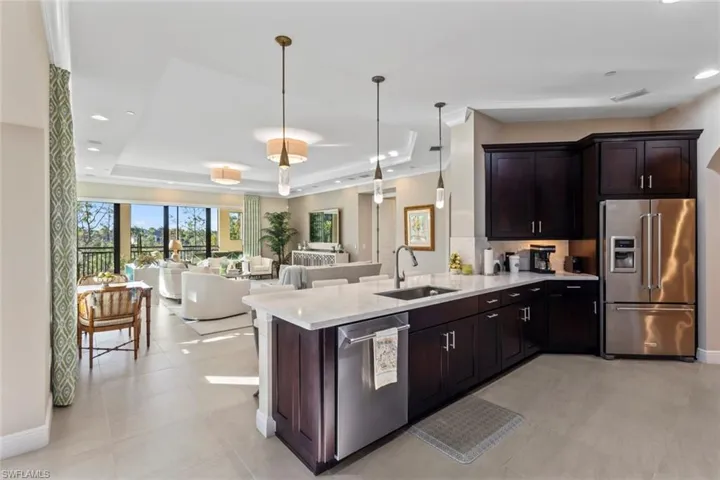 Kitchen with stainless steel appliances, pendant lighting, light stone countertops, recessed lighting, and open floor plan