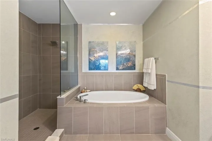 Full bath with a textured wall, walk in shower, a bath, and recessed lighting