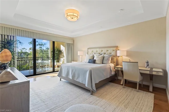 Bedroom featuring access to exterior, a tray ceiling, and light wood finished floors