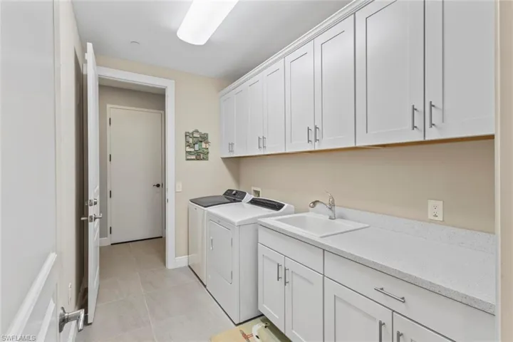 Washroom with cabinet space, independent washer and dryer, and light tile patterned floors