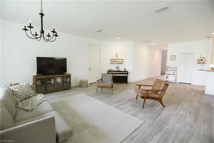 Living area with a chandelier, light wood finished floors, recessed lighting, and baseboards