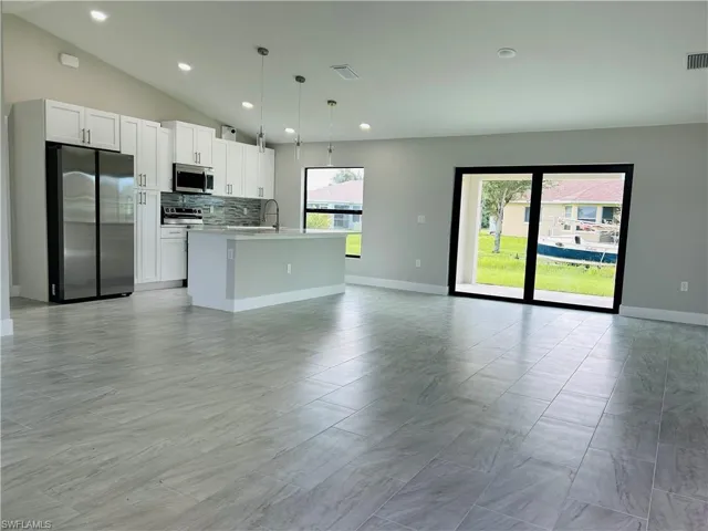 Kitchen featuring white cabinets, hanging light fixtures, sink, a kitchen island with sink, and appliances with stainless steel finishes