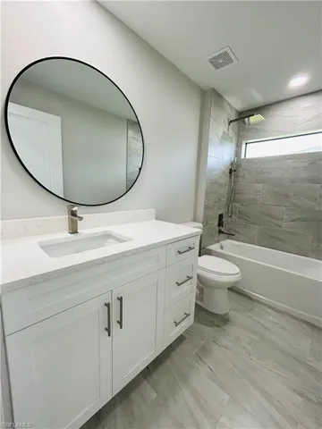 Full bathroom with tiled shower / bath combo, vanity, and toilet