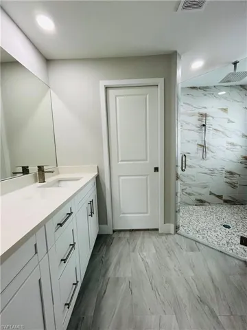 Bathroom featuring vanity and a shower with door
