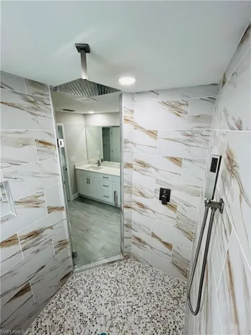 Bathroom featuring vanity, tile walls, and a shower with shower door