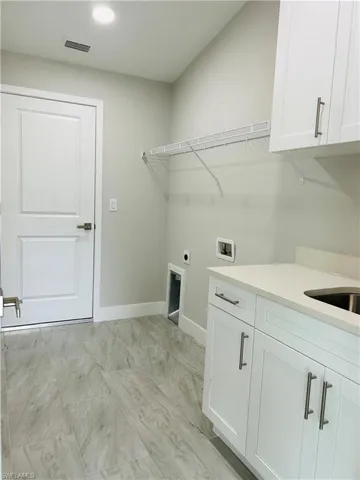 Laundry room with hookup for a washing machine, cabinets, and electric dryer hookup