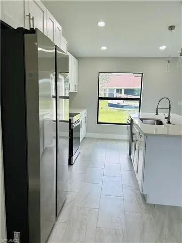 Kitchen featuring appliances with stainless steel finishes, white cabinetry, sink, and decorative light fixtures