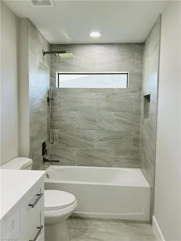 Full bathroom with plenty of natural light, vanity, toilet, and tiled shower / bath