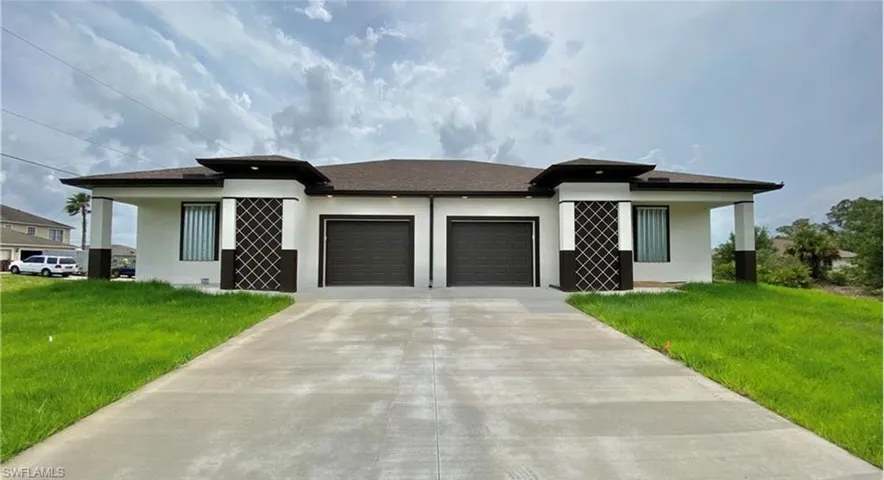 Modern duplex exterior featuring a clean white and dark brown color palette, a paved double driveway, and well-maintained green lawn areas