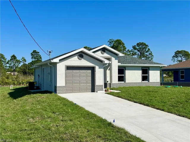 Single story home featuring a garage and a front lawn