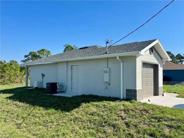 View of side of property featuring a garage, a yard, and cooling unit