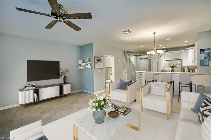 Unfurnished living room with sink, light tile patterned flooring, and ceiling fan with notable chandelier