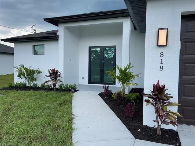 Entrance to property with stucco siding and a yard