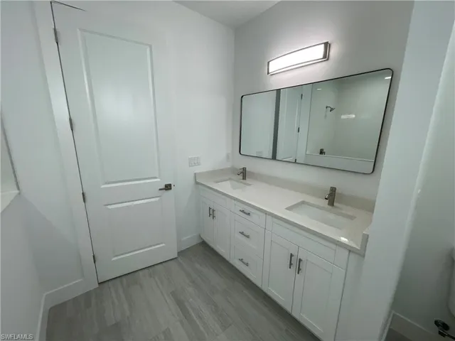 Bathroom featuring double vanity and light wood finished floors