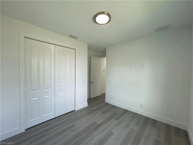Unfurnished bedroom with dark wood-style floors and a closet