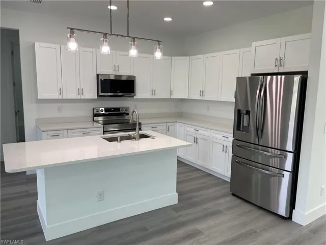 Kitchen featuring appliances with stainless steel finishes, dark wood-type flooring, white cabinets, and recessed lighting