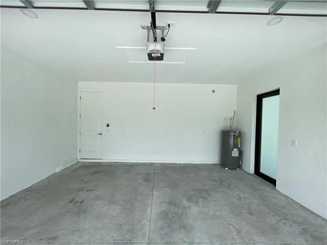 Garage featuring electric water heater and a garage door opener