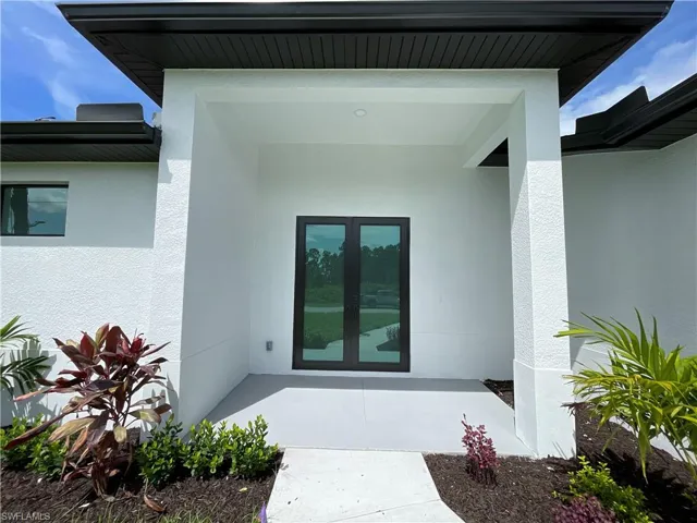 Property entrance with stucco siding, french doors, and a porch