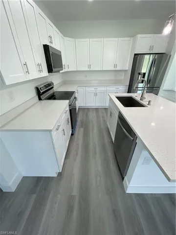 Kitchen with stove, light stone countertops, white cabinetry, and white refrigerator
