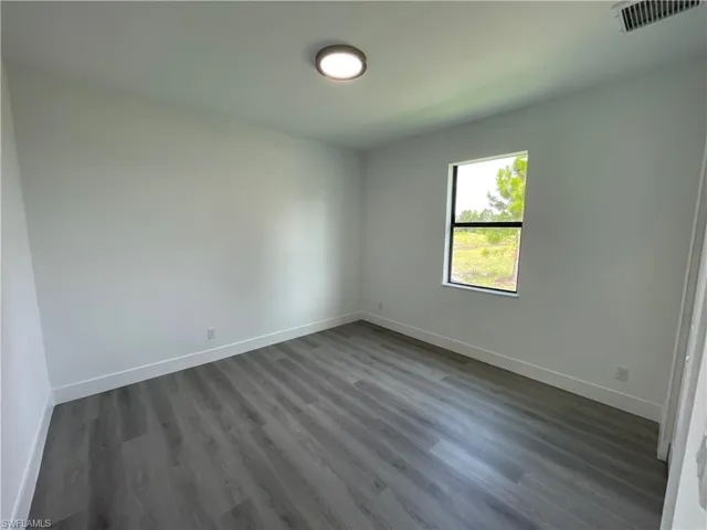 Unfurnished bedroom featuring dark wood finished floors and baseboards