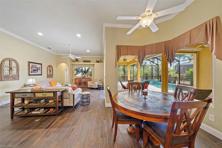 Dining space with a ceiling fan, crown molding, arched walkways, baseboards, and dark wood-type flooring