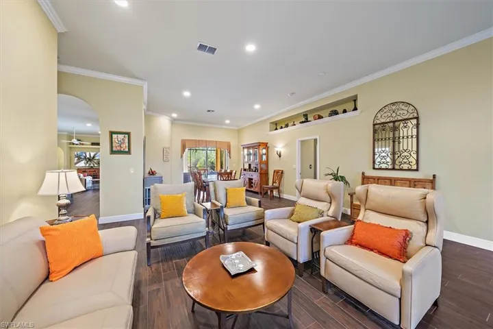 Living room featuring visible vents, baseboards, dark wood-style floors, recessed lighting, and arched walkways
