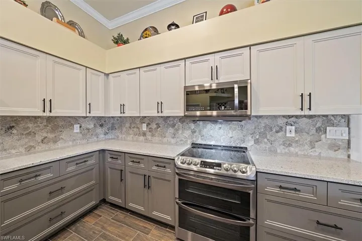 Kitchen with stainless steel appliances, ornamental molding, gray cabinets, and tasteful backsplash