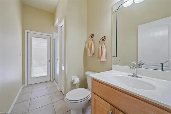 Bathroom with toilet, baseboards, tile patterned flooring, and vanity