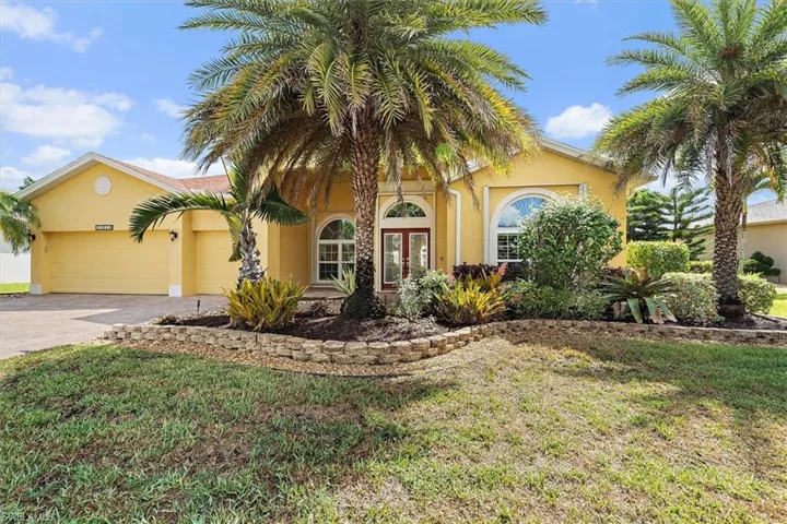 Mediterranean / spanish home featuring an attached garage, a front lawn, aphalt driveway, stucco siding, and french doors