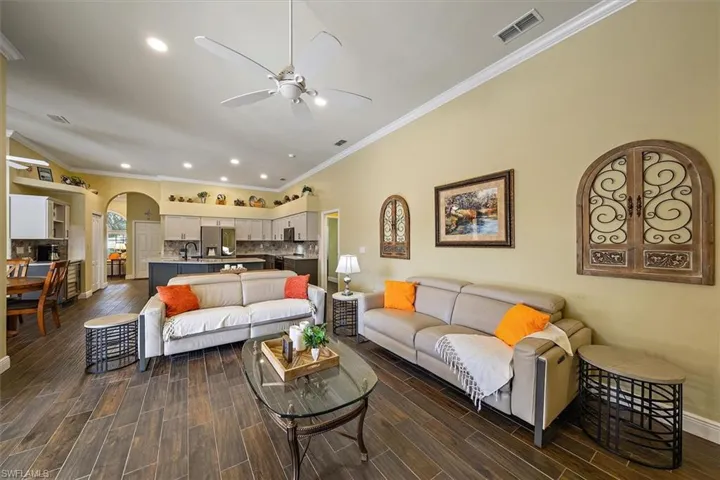 Living area featuring visible vents, ceiling fan, recessed lighting, arched walkways, and dark wood finished floors
