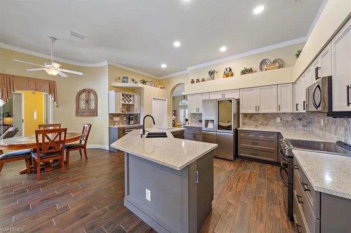 Kitchen with ornamental molding, an island with sink, stainless steel fridge with ice dispenser, a sink, and double oven range