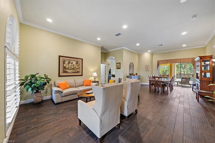Living room with visible vents, arched walkways, dark wood finished floors, baseboards, and recessed lighting