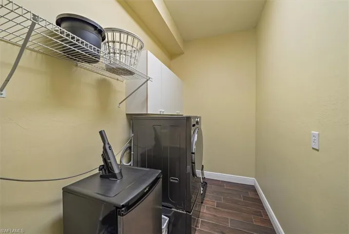 Laundry area with separate washer and dryer, baseboards, wood tiled floor, and cabinet space