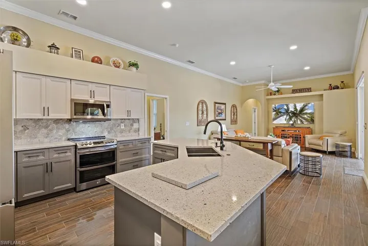 Kitchen with dark wood-style flooring, a sink, arched walkways, stainless steel appliances, and visible vents