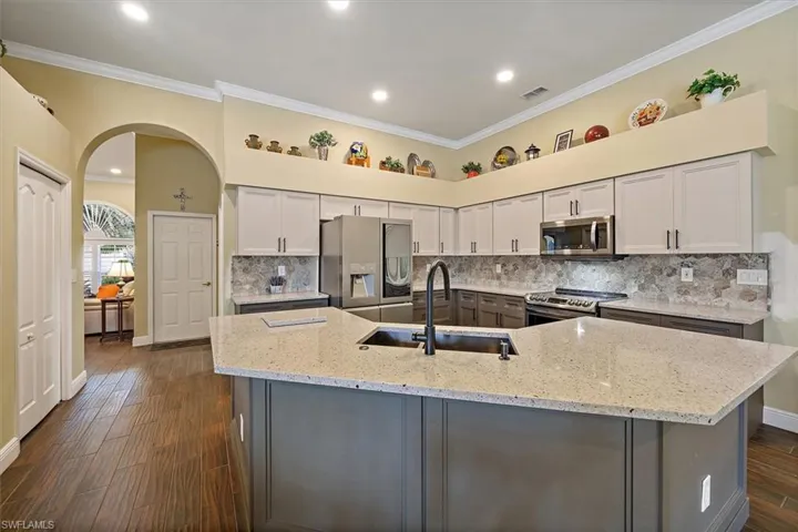 Kitchen featuring visible vents, crown molding, arched walkways, a sink, and stainless steel appliances