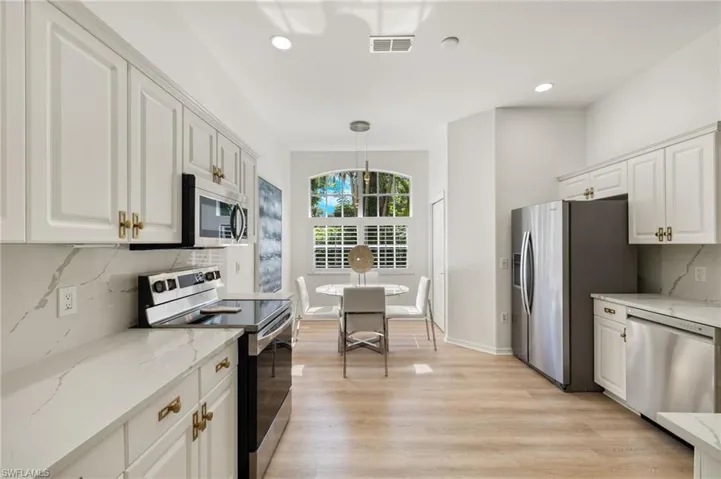 Kitchen featuring stainless steel appliances, LVP flooring, backsplash, and quartz counters