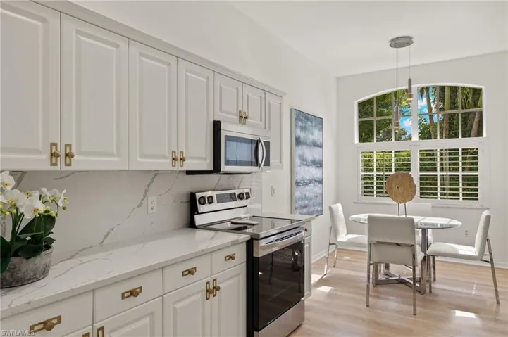 Kitchen featuring stainless steel appliances, LVP flooring, backsplash, and quartz counters