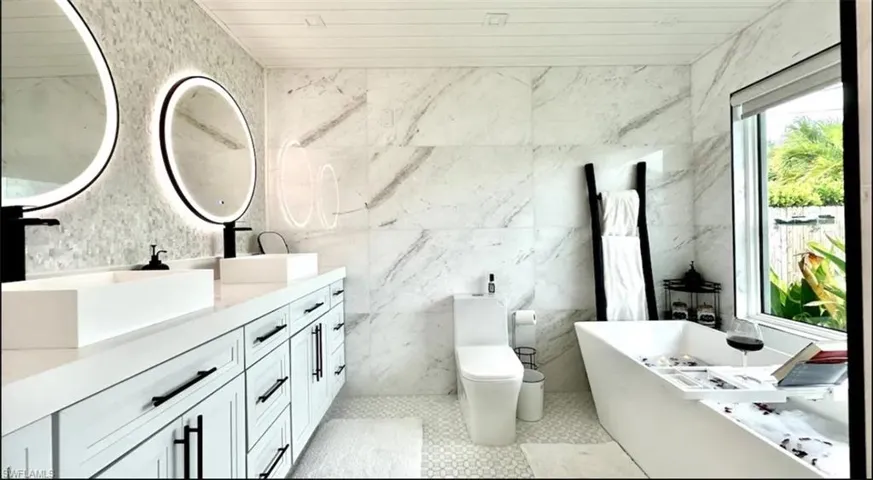 Full bath with double vanity, a freestanding bath, tile walls, and wood ceiling