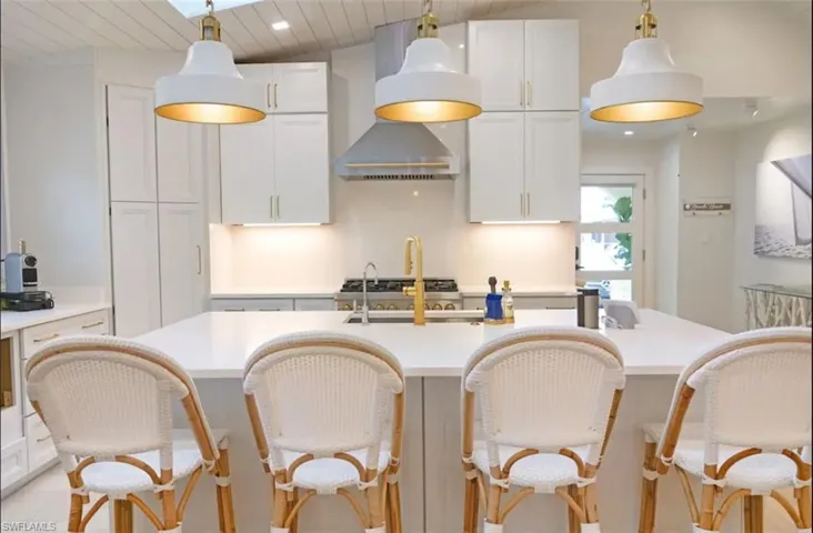 Kitchen featuring white cabinetry, a center island with sink, hanging light fixtures, a vaulted wood ceiling, and a kitchen breakfast bar