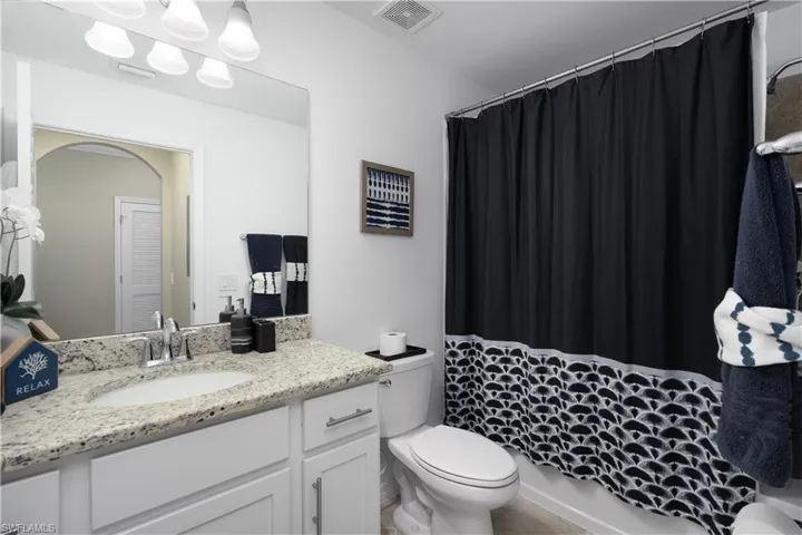 Full bath with toilet, vanity, visible vents, and a shower with curtain